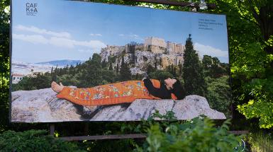 A billboard depicting the artist laying on the ground in the mountains under a silk blanket.