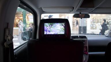 View of a video screen in a driver seat headrest of a vehicle, displaying the words "is associated with creation"
