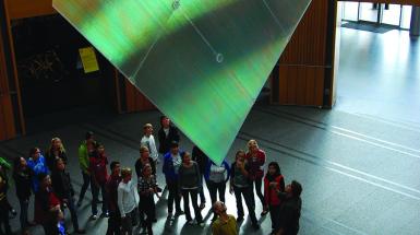 an audience looking at a sculpture hanging from the ceiling