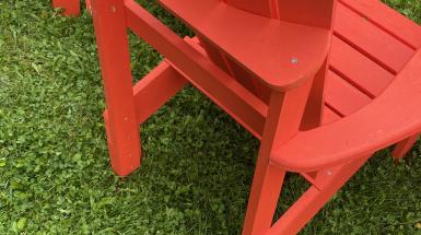 Vibrant red Muskoka chairs on a clover lawn