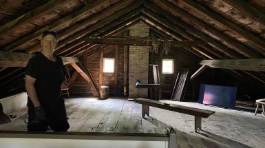 A man smiles in the attic room of an old house