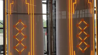 Installation photo of 'Gates' by Roda Medhat, a large inflatable gate enclosed in an acrylic and steel box with LED "neon" lights depicting a Kurdish designs