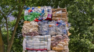 The top of the monument – bales of cardboard, plastic containers, and fibres – against a background of tree canopy.