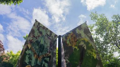 The top of two banners, outstretched like wings, with a blue cloudy sky behind.