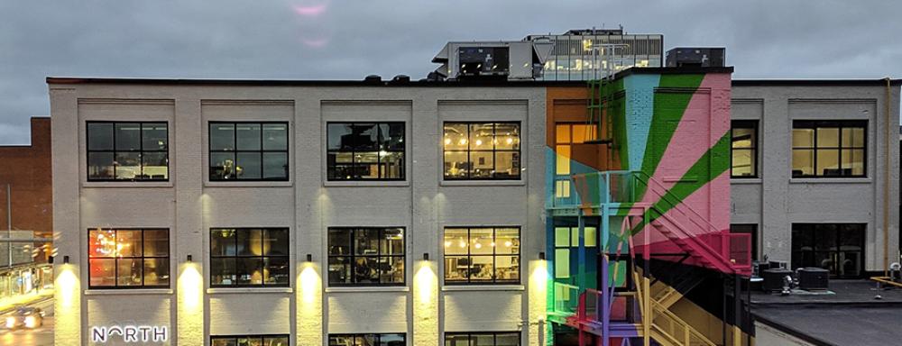 Building with colourful geometric mural on the fire escape stairs. 