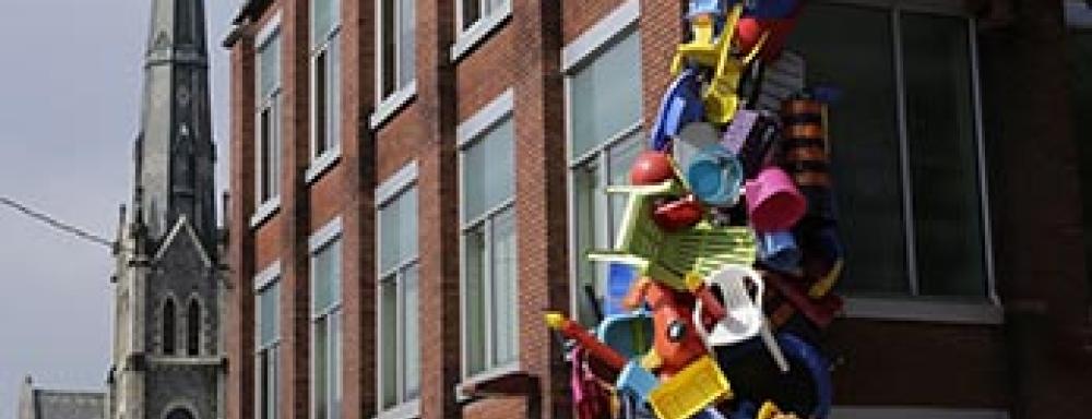 Building with a variety of plastic colourful objects crawling up the corner of it. 