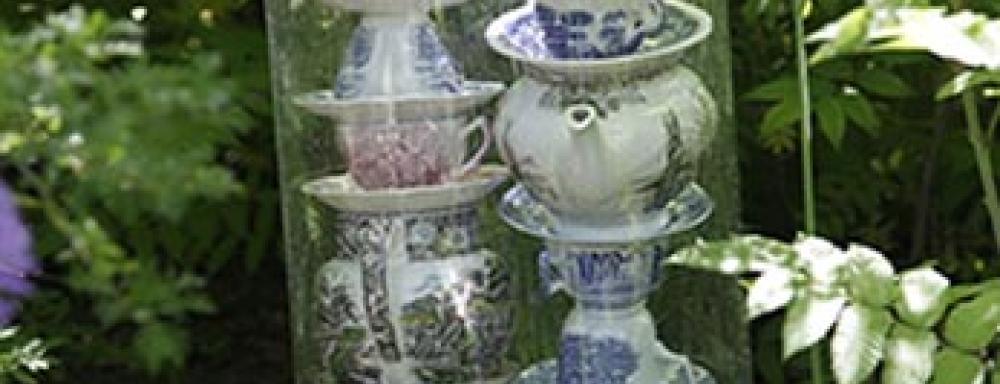 Teacups stacked on top of each other in a plastic covering placed in a garden. 