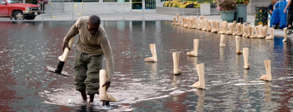 a man placing wooden feet in shallow man made pond. 