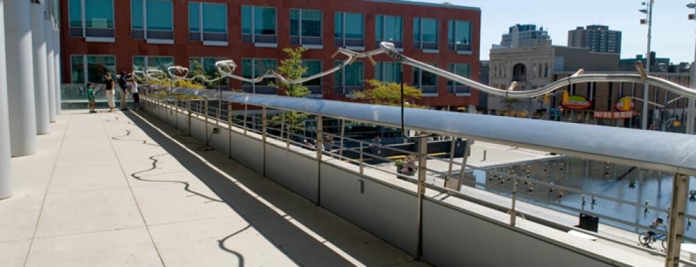 A railing which is wavy and has wooden tool handles protruding from it. 