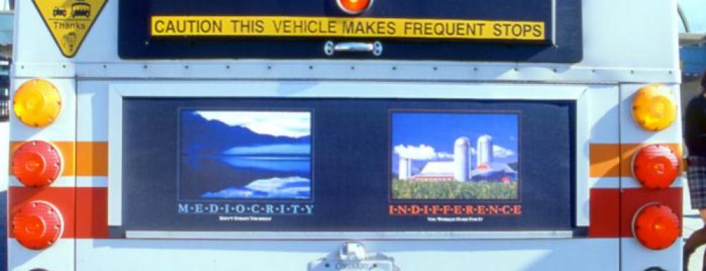 back of bus with two images one of a lake the other a farm with text that read mediocracy and indifference