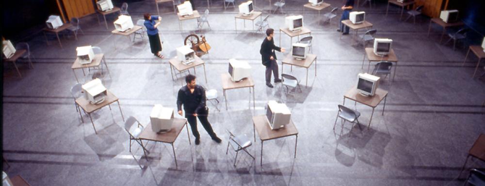 room filled with tables and chairs set up in circles which has desktop computers on top
