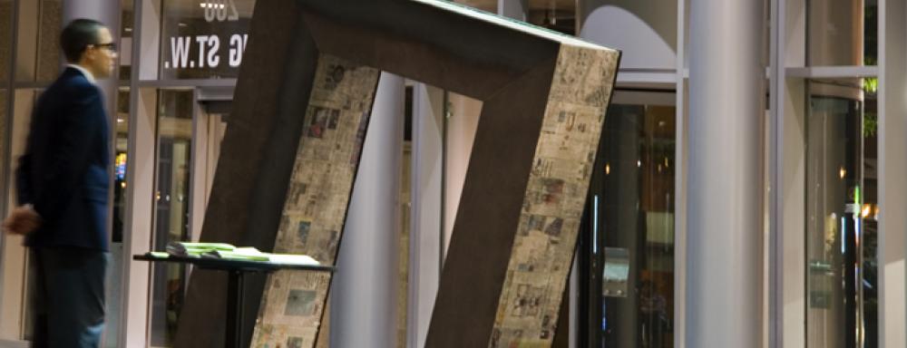 Man in suit observing titles rectangular sculpture