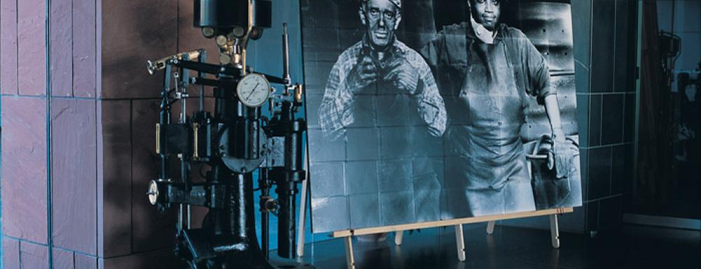 Image of metal machine beside photograph of two blue collar workers