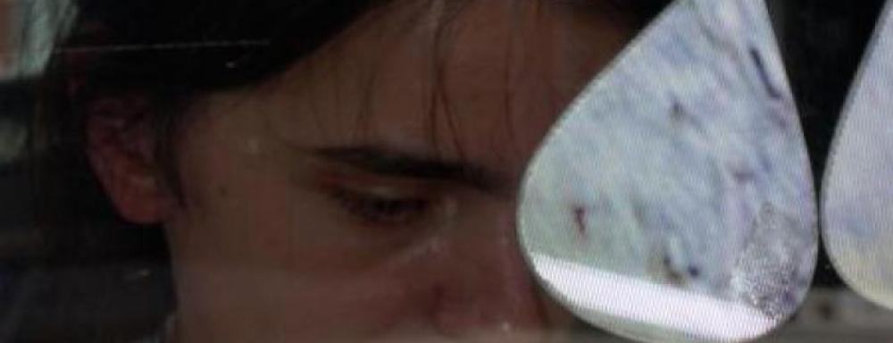 Person crying with three water droplet shapes project on glass in front