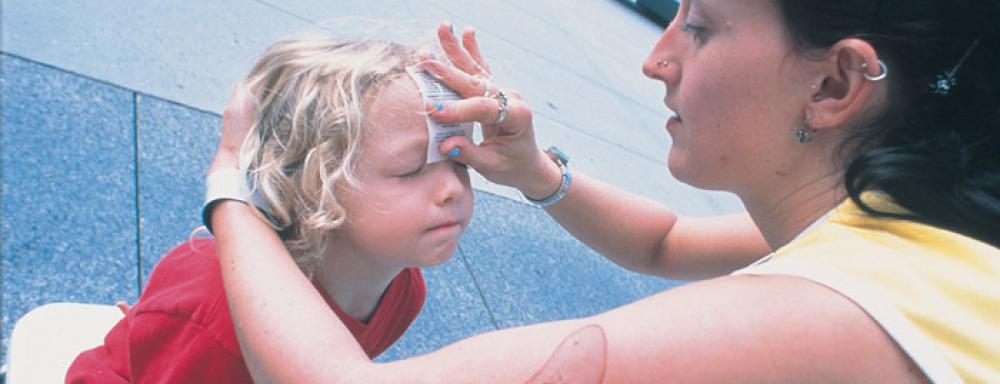 Woman putting temporary tattoo on child's forehead