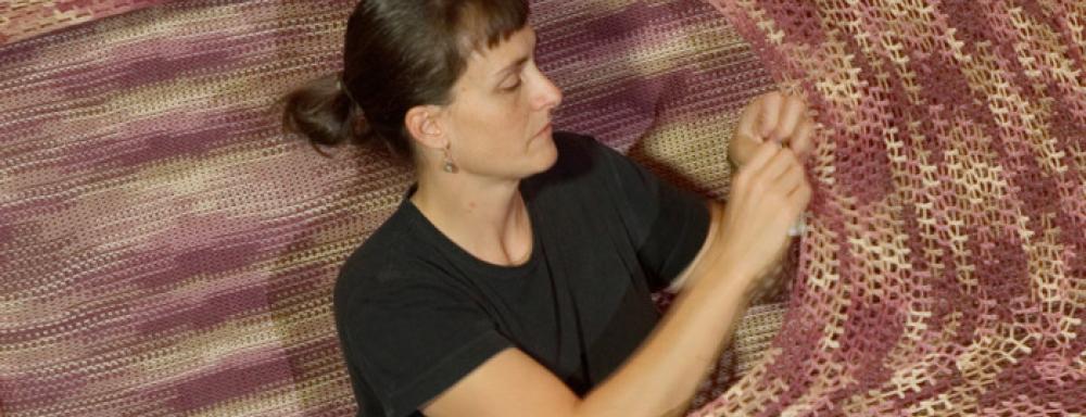 Artist crocheting inside large crochet project