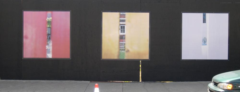 Three photographs on wall that have colour on ether side with sliver that show a building through it. 