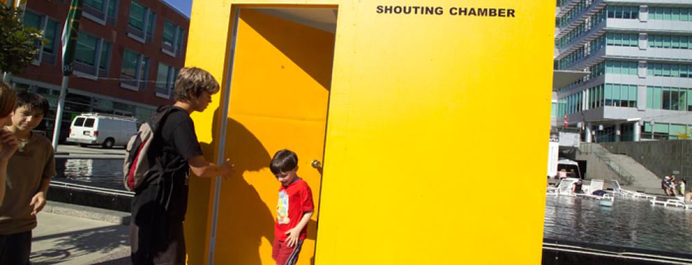 A young boy coming out of yellow box/room that says shouting chamber