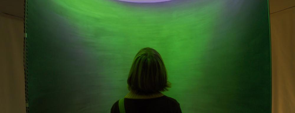 Figure looking up a circular room filled with green light
