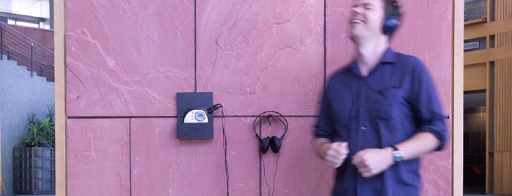 Person listening to Disc-man which is suspened from wall. Seems to be dancing