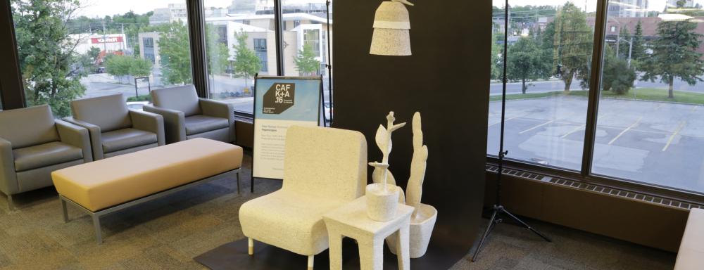 A chair, side table, plants and lamp with bird on top made of paper