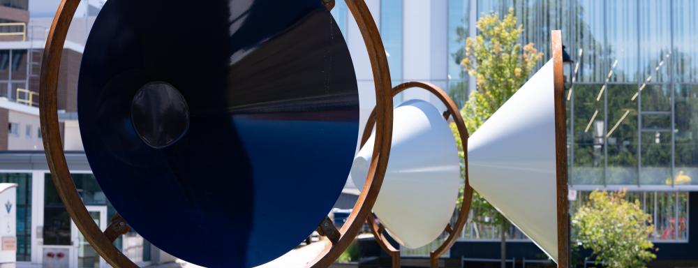 Three metal cones facing outward in a semi-circle on metal frames in the middle of a field.