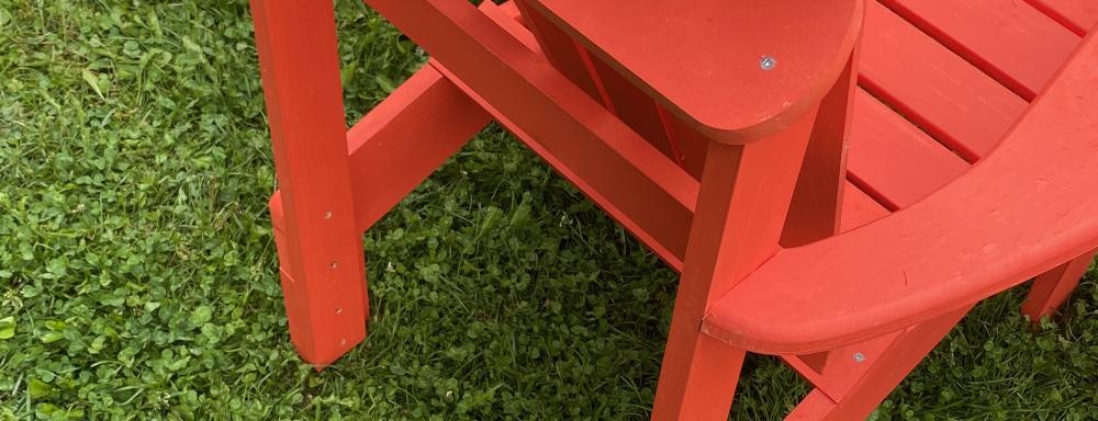 Vibrant red Muskoka chairs on a clover lawn