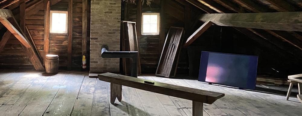 A man smiles in the attic room of an old house
