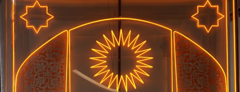 Installation photo of 'Gates' by Roda Medhat, a large inflatable gate enclosed in an acrylic and steel box with LED "neon" lights depicting a Kurdish designs