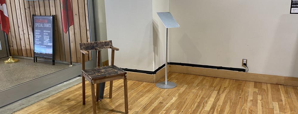 A chair covered in photo-transfers sits in a lobby with a large window behind it