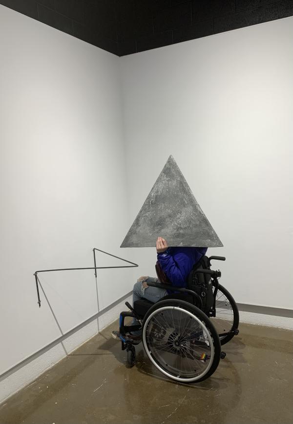 a person in a wheelchair wearing the triangular concrete helmet