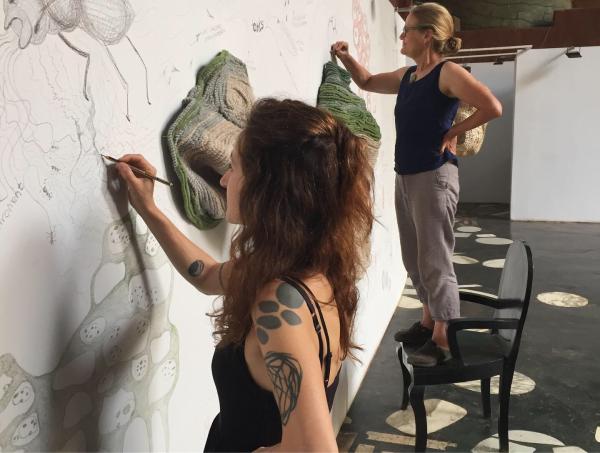 ZAC members collectively drawing on a white wall interspersed with objects