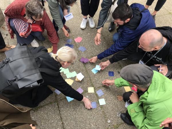 Group of people kneeling around several colourful post-it notes on a sidewalk