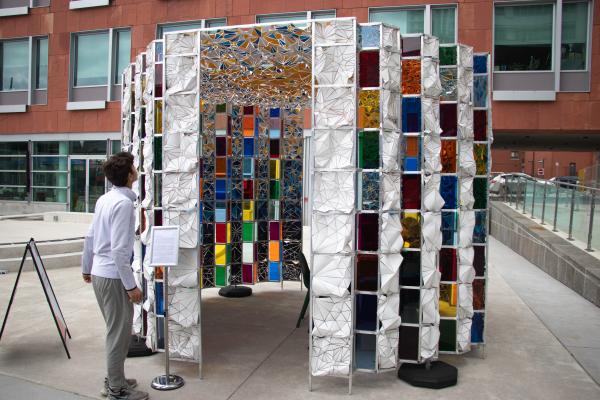 A youth admiring a large sculpture of multicoloured cloth mosaics.