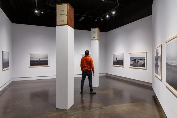 Man in red jacket looking up at filing cabinet of tall plinth