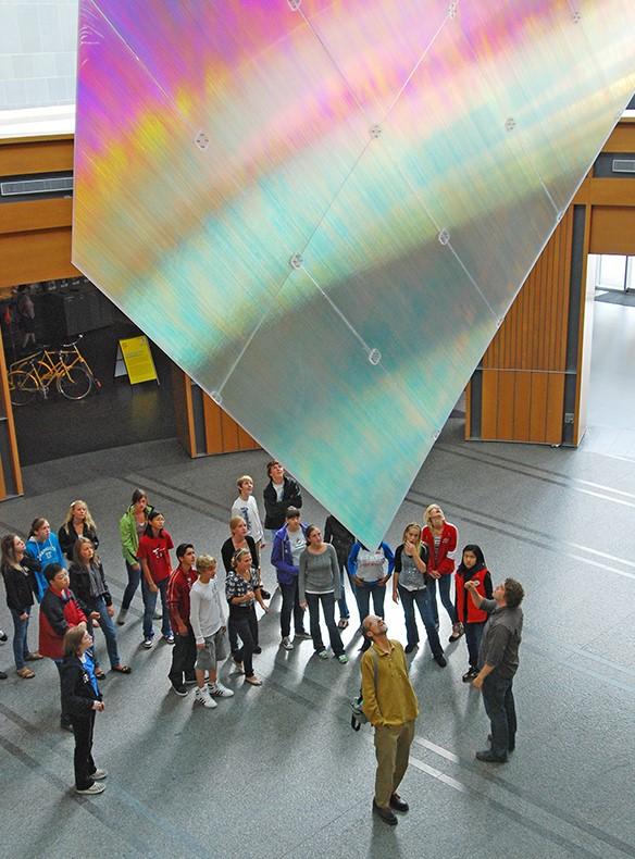 Group of students looking up at large holographic sheet 