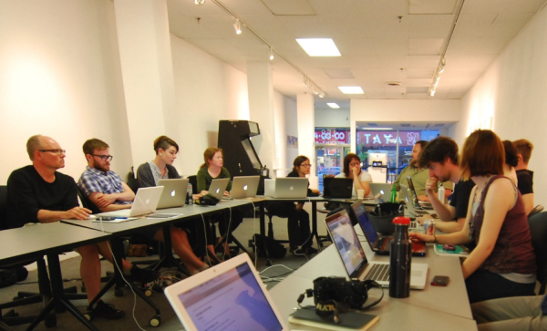 Individuals around a table look at laptops