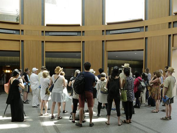 back of crowd standing and watching someone talk