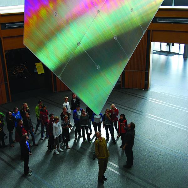 an audience looking at a sculpture hanging from the ceiling