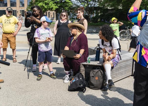 A group of community members of all different ages sitting and standing together while watching a performance.